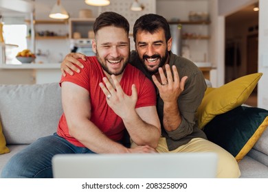 Young happy gay couple in love just got married so they have a video call with their friends and family to spread the joy. The couple showing their wedding rings. - Powered by Shutterstock