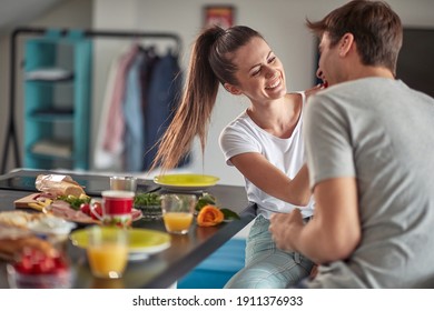 A young happy girl feeding her boyfriend at a breakfast in a cheerful atmosphere at home. Couple, love, breakfast, together