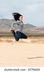 A Young Happy Girl Jumping In The Nevada Desert ( Dry Lake Bed)