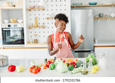 Young happy girl singing in the kitchen