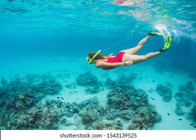 Joven feliz saltando con máscara de buceo y buceando bajo el agua para ver peces tropicales en la piscina del arrecife de coral. Actividades de viajes, deportes náuticos, aventura al aire libre, vacaciones familiares en playa de verano con niños