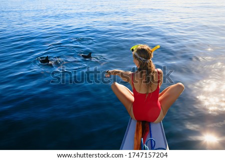 Young happy girl in snorkeling mask sit no boat. Dolphins watching adventure tour on tropical islands. Water activity, active children lifestyle, summer vacation travel with kids at family resort.