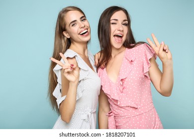 Young happy girlfriends in fashion dresses on blue background
