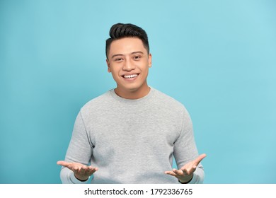 Young happy handsome Asian man raising his hands with open palms gesture