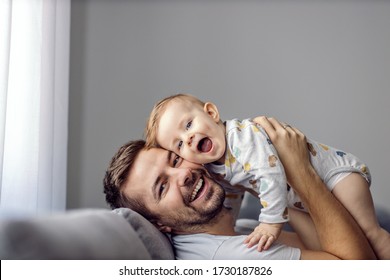 Young happy handsome father holding his beloved only little son, having fun. Toddler and dad are looking at camera and smiling. - Powered by Shutterstock