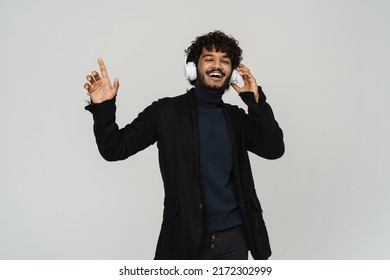 Young Happy Handsome Indian Man Dancing In Headphones Over Isolated Grey Background