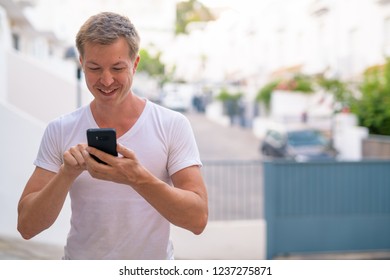 Young Happy Handsome Man Using Phone In The Streets Outdoors
