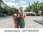 Young happy hipster backpacker travelers couple, visiting new country, summer travel destination, enjoying their vacation, walking down the city streets, looking historical buildings and architecture.