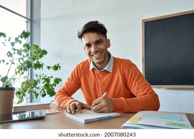 Young happy Hispanic Indian latin student gen z hipster having virtual distant class course with teacher writing notes looking at camera. Education technologies concept. Webcam view portrait.