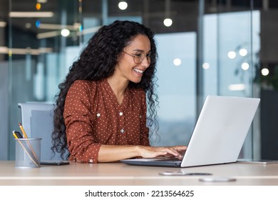 Young and happy hispanic woman working in modern office using laptop, business woman smiling and happy in glasses and curly hair - Powered by Shutterstock