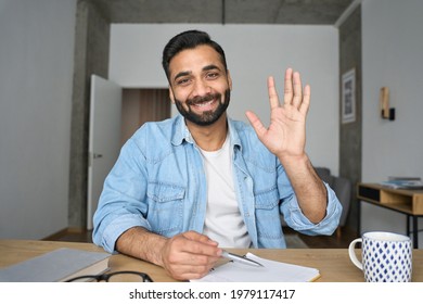 Young happy indian Hispanic arab teacher talking on video conference call greeting waving hand using laptop at modern home office. Remote distant online work education techs concept. Webcam view.