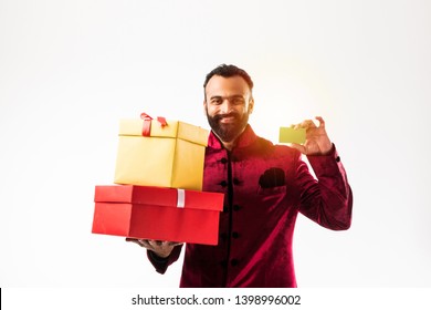 Young Happy Indian Man With Beard Holding Gift Box And Empty Card While Wearing Traditional Cloths /sherwani, Standing Against White Background