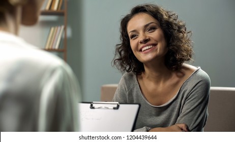 Young happy lady talking with psychologist at clinic, session of rehab therapy - Shutterstock ID 1204439644