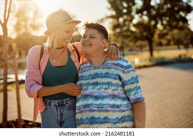 Young Happy Lesbians Having Fun While Walking In The Park At Sunset.