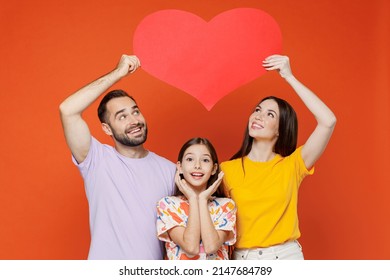 Young Happy Lovely Fun Parents Mom Dad With Child Kid Daughter Teen Girl In Basic T-shirts Hold Big Red Heart Above Head Isolated On Yellow Background Studio. Family Day Parenthood Childhood Concept.