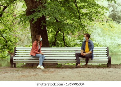 Young, happy, loving couple having date in the park during the coronavirus lockdown crisis. Relations, friendship and love concept. Social distancing and virus protection.