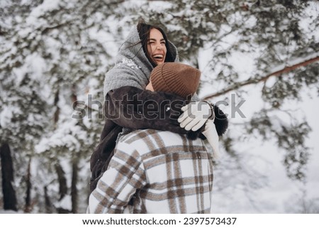 A young happy and loving couple walking in a winter snowy forest in the mountains