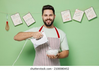 Young Happy Male Chef Confectioner Baker Man 20s In Striped Apron Using Mixer Whisk Eggs For Cake Dessert Cooking Isolated On Plain Pastel Light Green Background Studio Portrait. Cooking Food Concept