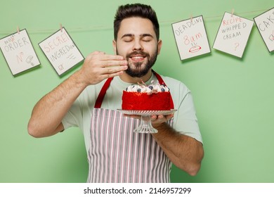 Young Happy Male Chef Confectioner Baker Man 20s In Striped Apron Hold Birthday Sweet Dessert Cake Sniff Scent Isolated On Plain Pastel Light Green Background Studio Portrait. Cooking Food Concept.