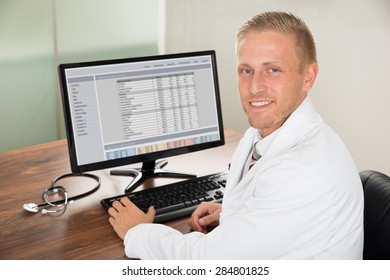 Young Happy Male Doctor Working On Computer At Desk