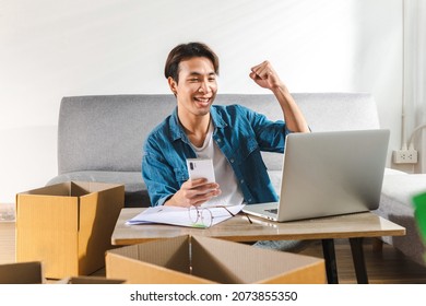 A young happy male entrepreneur at home works on a laptop computer and online checks orders to prepare to pack the parcel boxes, sell to customers, Online Selling shopping, and business ideas online.