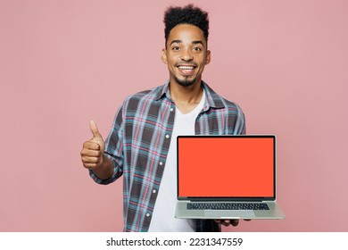 Young happy man of African American ethnicity 20s he wear blue shirt hold use work on laptop pc computer with blank screen workspace area show thump up isolated on plain pastel light pink background - Shutterstock ID 2231347559