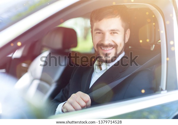 Young\
happy man in car smiling - concept of buying\
car