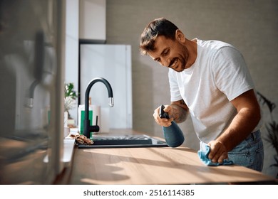 Young happy man cleaning kitchen counter at home. Copy space.  - Powered by Shutterstock