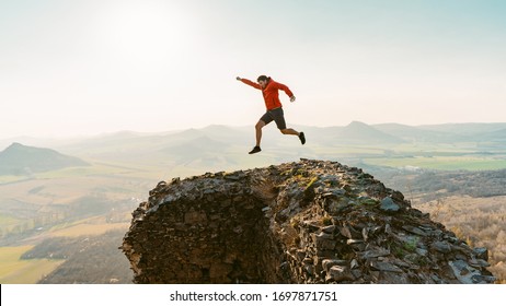 Young happy man high jumping on castle ruins. Admires the beauty of nature. Looks at the horizon. Sunny spring day