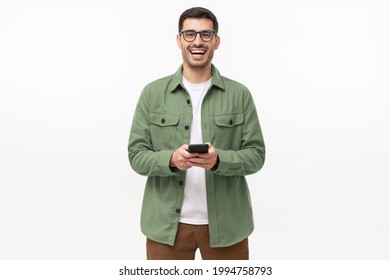 Young happy man laughing as he is looking at camera, holding his phone, isolated on gray background - Powered by Shutterstock