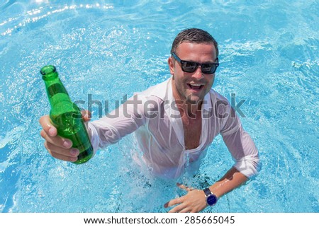 Young happy man partying in swimming pool