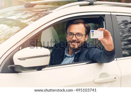 young happy man showing his new driver license