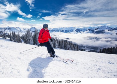 Young happy man skiing in Kitzbuehel ski resort and enjouing the beautiful weather with blue sky and Alpine mountains in Austria. 
