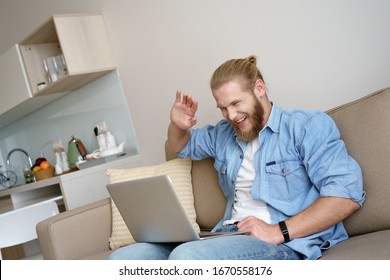 Young Happy Man Student Hipster Freelancer Modern Laptop Pc Chat Online Use Skype Zoom Hangout Call Wave Hello Hi, Smiling Guy Look At Screen Web Camera Video Calling Sit Relax On Sofa Couch At Home.