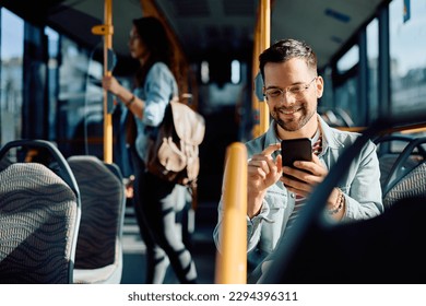 Young happy man using mobile phone while riding in city bus.  - Powered by Shutterstock