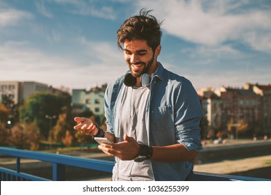 Young Happy Man Using A Smartphone  In The City