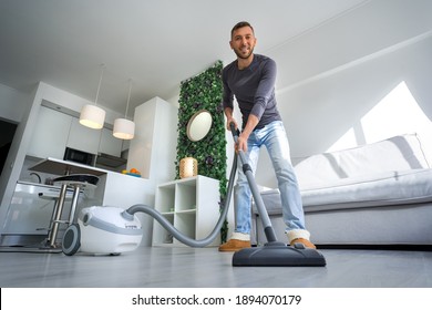 Young Happy Man Vacuuming At Home. Man Cleaning House With Vacuum Cleaner. House Keeping 