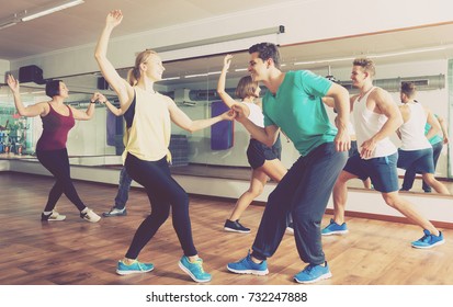 Young happy men and women dancing swing in dance hall
