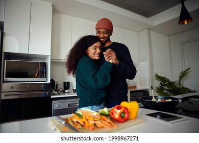 Young, Happy Mixed Race Couple Holding Hands In The Kitchen. Mixed Race Couple Dancing Together And Having Fun. High Quality Photo