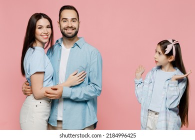 Young Happy Mom Dad With Sad Jelaous Child Kid Daughter Teen Girl Wearing Blue Clothes Look At Hugging Parents Spread Hands Isolated On Plain Pastel Light Pink Background. Family Day Childhood Concept