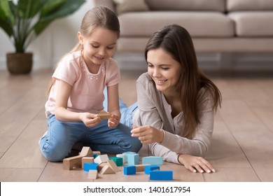 Young Happy Mom And Preschooler Daughter Sit On Floor Playing With Toy Blocks Together, Smiling Mother Or Nanny And Little Girl Child Have Fun Engaged In Funny Activity Game With Building Bricks