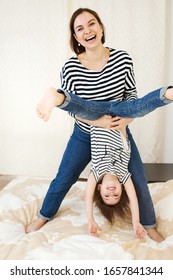 Young Happy Mother Having Fun With Her Cute Little Baby Holding Her Upside Down, Playing And Laughing, Active Games At Home, Full Body