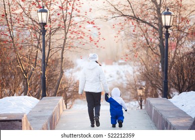 Young Happy Mother With Her Baby Son Enjoying Beautiful Cold Winter Sunny Day. Happy Family Lifestyle Concept With Sunshine And Blue Sky, Back Silhouette View