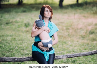 Young happy mother holding newborn baby boy in her hands outdoors in summer in sun rays, baby boy in rabbit costume - Powered by Shutterstock