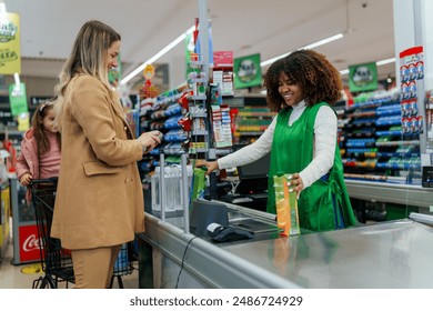 A young happy mother with a little girl is talking to the cashier at the supermarket checkout. - Powered by Shutterstock