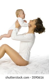 Young Happy Mother Picking Up Baby. Woman Is Sitting In Bed And Holding Baby. White Background