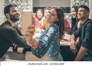 Young happy multiracial cheerful friends having fun making selfie on the table of the kitchen.  - Powered by Shutterstock