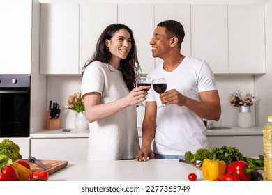 young happy multiracial couple drink wine in white modern kitchen, african american guy clink glasses with girl, interracial family celebrate holiday and drink alcohol - Powered by Shutterstock