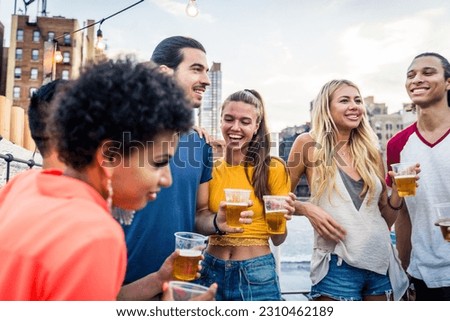 Young happy multiracial people having a barbecue dinner on a rooftop in New York - Group of multiethnicfriends having party and having fun on apartment terrace
