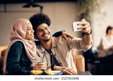 Young Happy Muslim Couple Taking Selfie With Smart Phone In A Cafe.